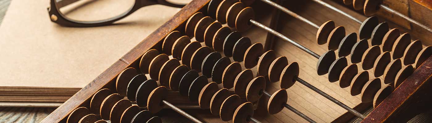 cropped photo of an old wooden calculator/counter sitting on a wooden desk on top of light brown paper