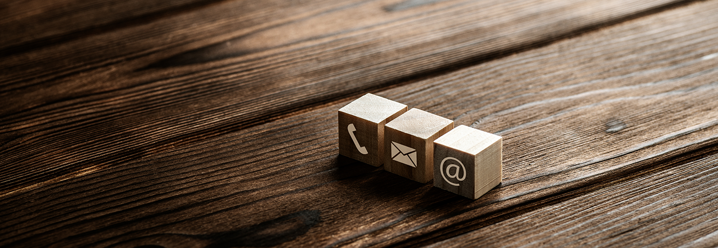 three wooden blocks on a hardwood floor with icons for phone and email on them.